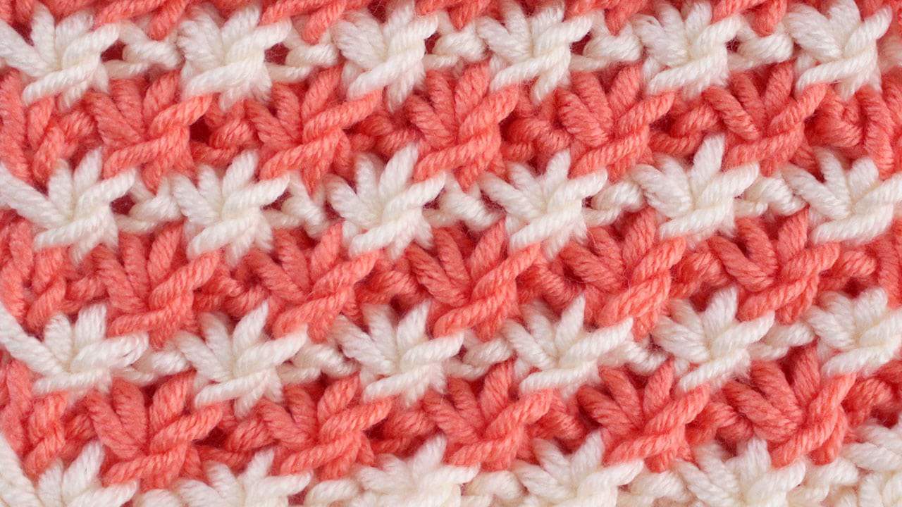 Swatch of Daisy Stitch knitted in orange and white yarn.