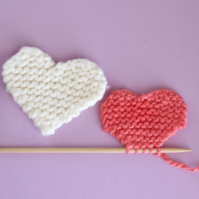 Two knitted hearts in garter stitch knitted in white and pink yarn colors.