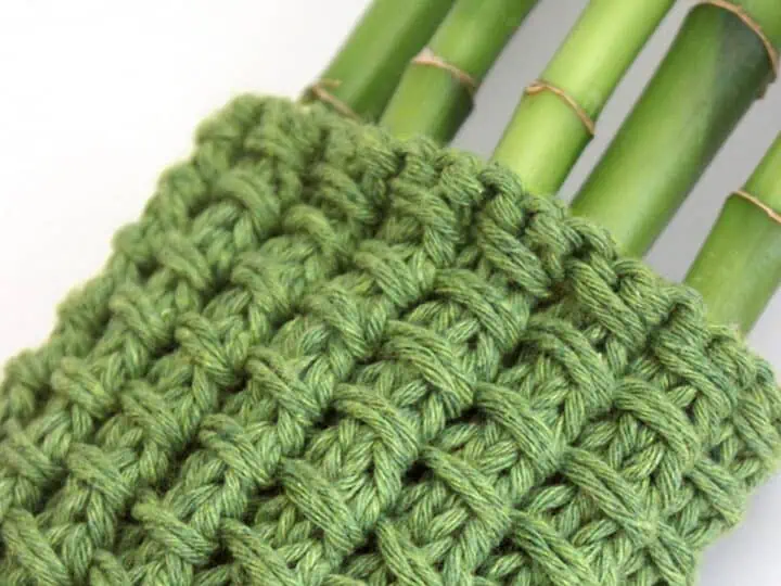 Knitted Bamboo Stitch Pattern swatch in green color yarn wrapped around bamboo stalks.