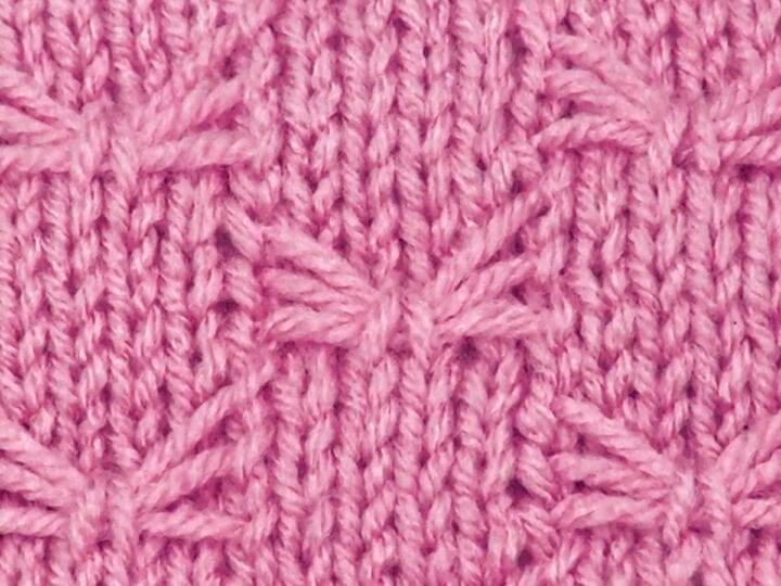 Knitted butterfly stitch pattern in pink color yarn.