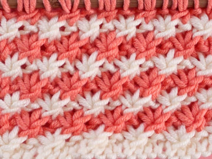 Daisy Stitch Knitting Pattern texture in alternating orange and white colors of yarn on knitting needle.