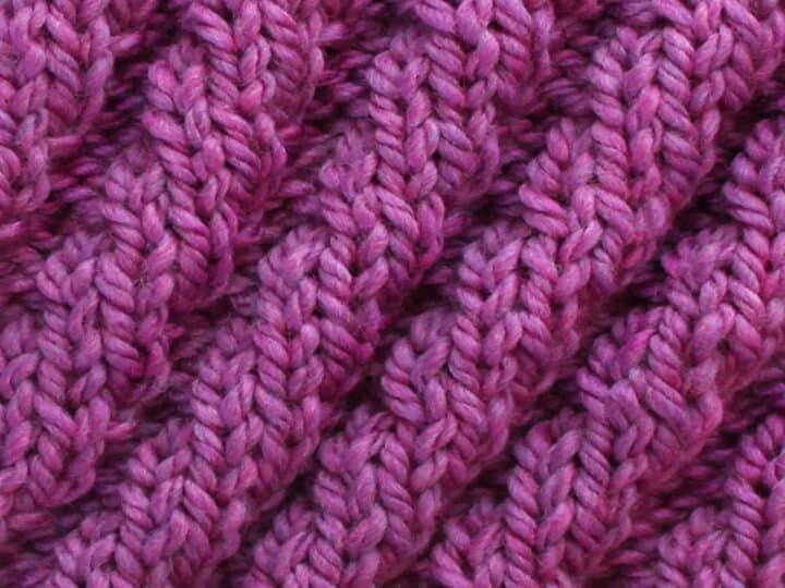 Knitted Diagonal Spiral Rib Stitch Pattern texture in purple color yarn.