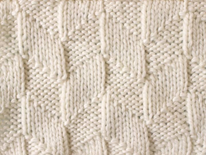 Parallelogram Knit Stitch Pattern texture in white yarn on knitting needle.