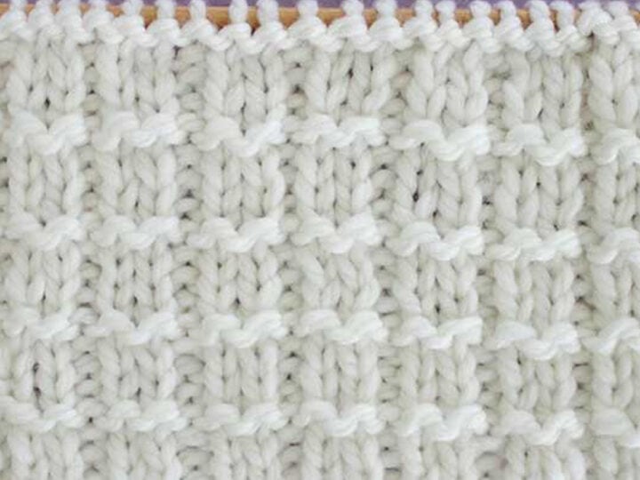 Pique Rib Knit Stitch Pattern in white yarn on knitting needle.