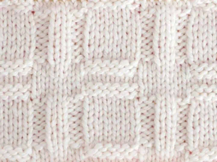 Knitted Window Stitch Pattern in white yarn on knitting needle.