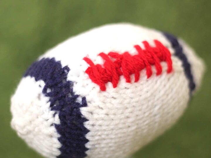 Knitted Football softie toy in white, blue, and red yarn colors.