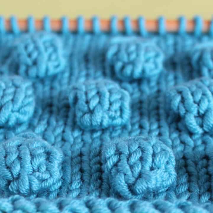 Bobbles in Stockinette Stitch on knitting needle in blue color yarn.