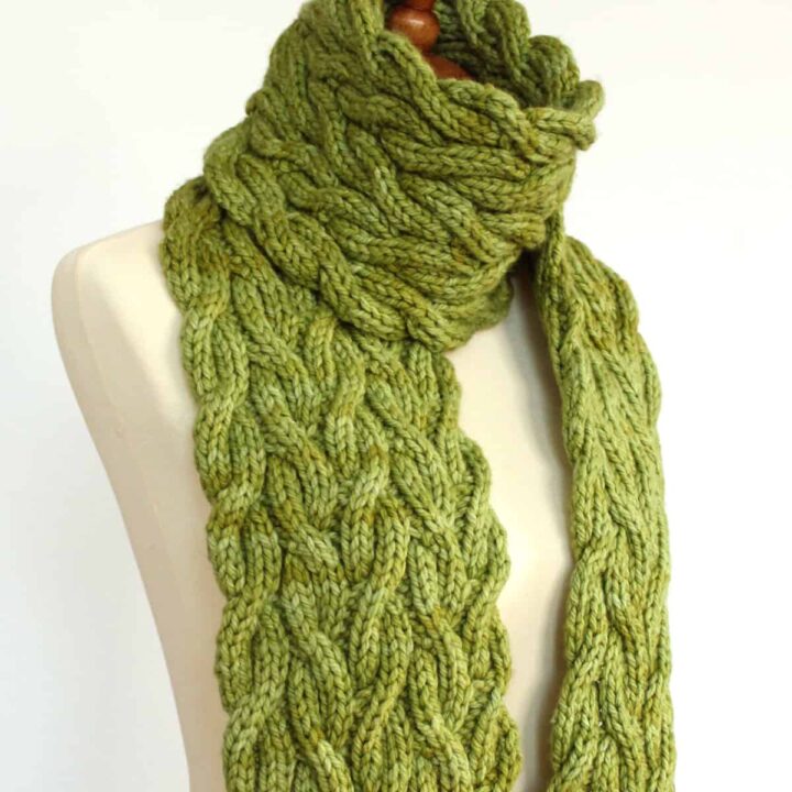 Meadow Vine Reversible Cable Scarf in green yarn displayed on mannequin.