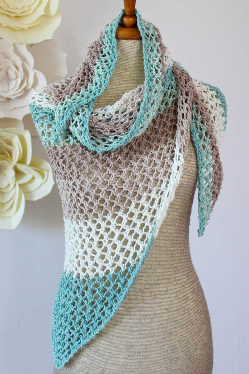 Knitted mesh shawl in displayed on a mannequin in colors blue, brown, and white.