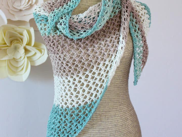 Knitted mesh shawl in displayed on a mannequin in colors blue, brown, and white.