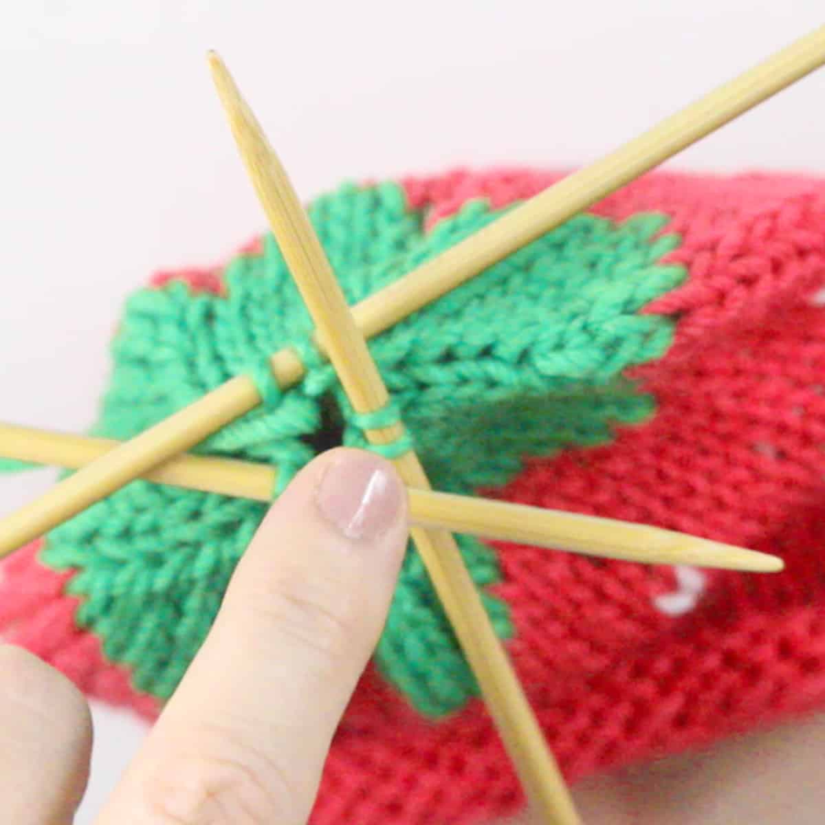 Knitting the topper of the strawberry baby hat with three double pointed needles.