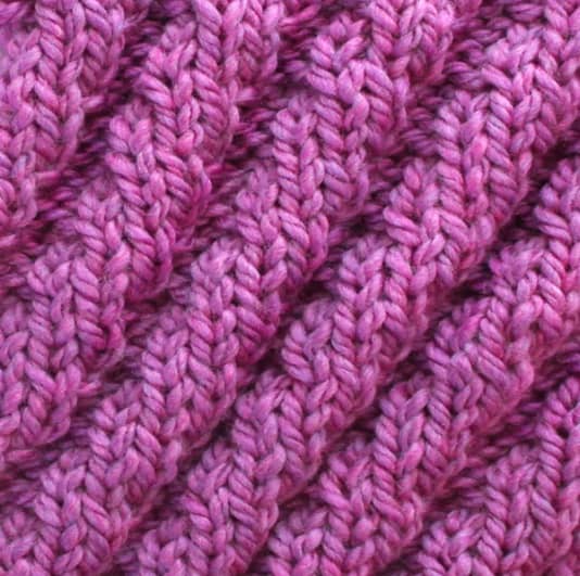 Diagonal spiral knit stitch pattern in purple colored yarn.