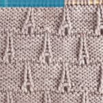 The Eiffel Tower knitting pattern in gray colored yarn on a knitting needle by Studio Knit.