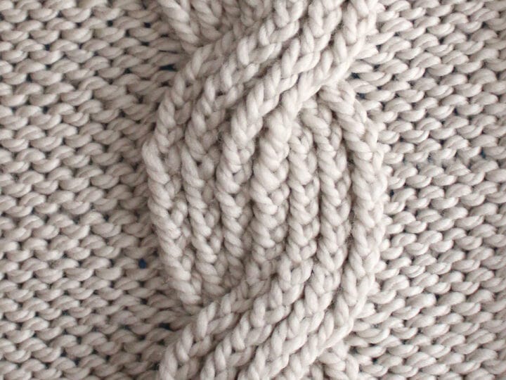 Seven seas cable ribbing knit stitch pattern in beige colored yarn.