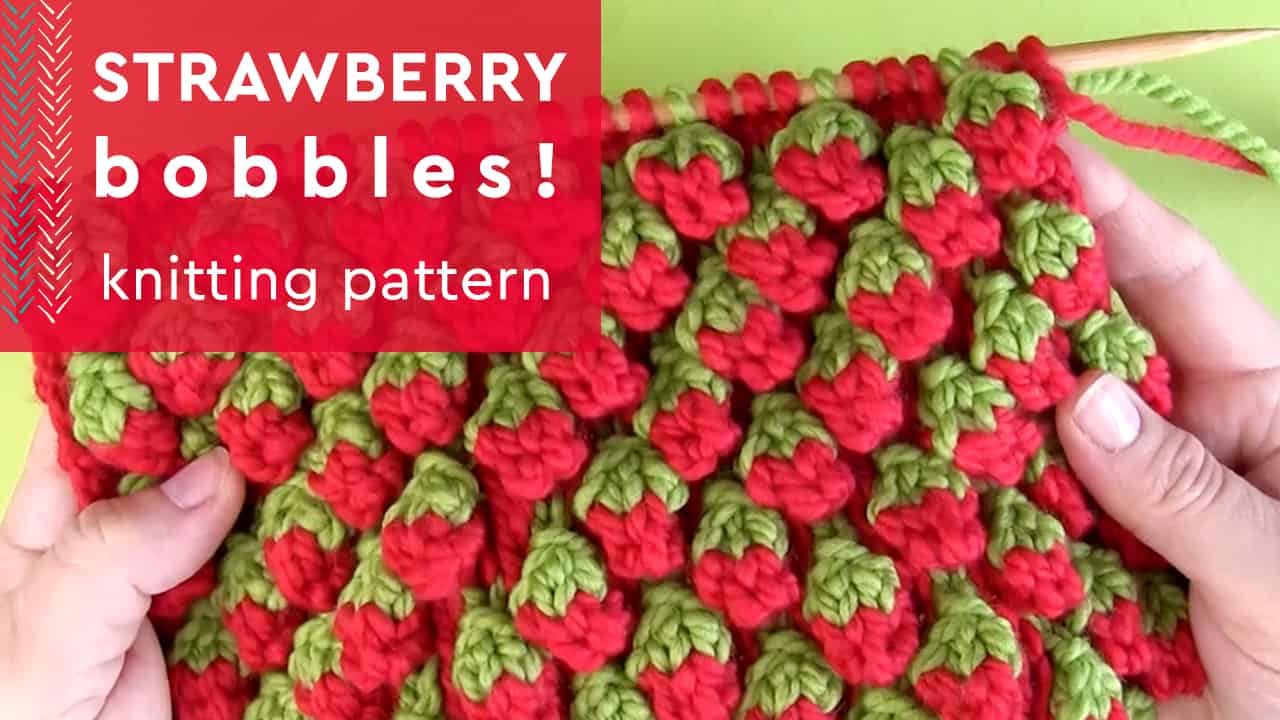 Strawberry Bobbles knitting pattern with texture knitted in red and green yarn colors on wooden needle.