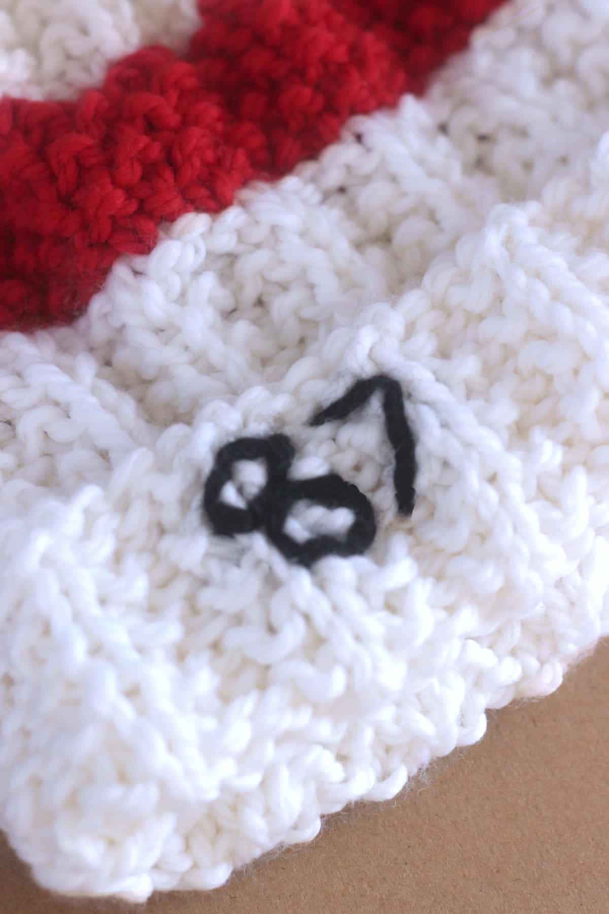 Embroidery of number 87 on a knit hat.