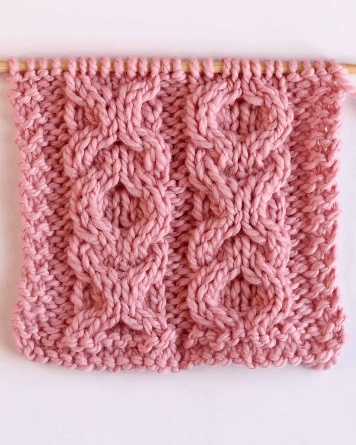 XO Cable textured pattern knitted on straight needles with pink colored yarn.