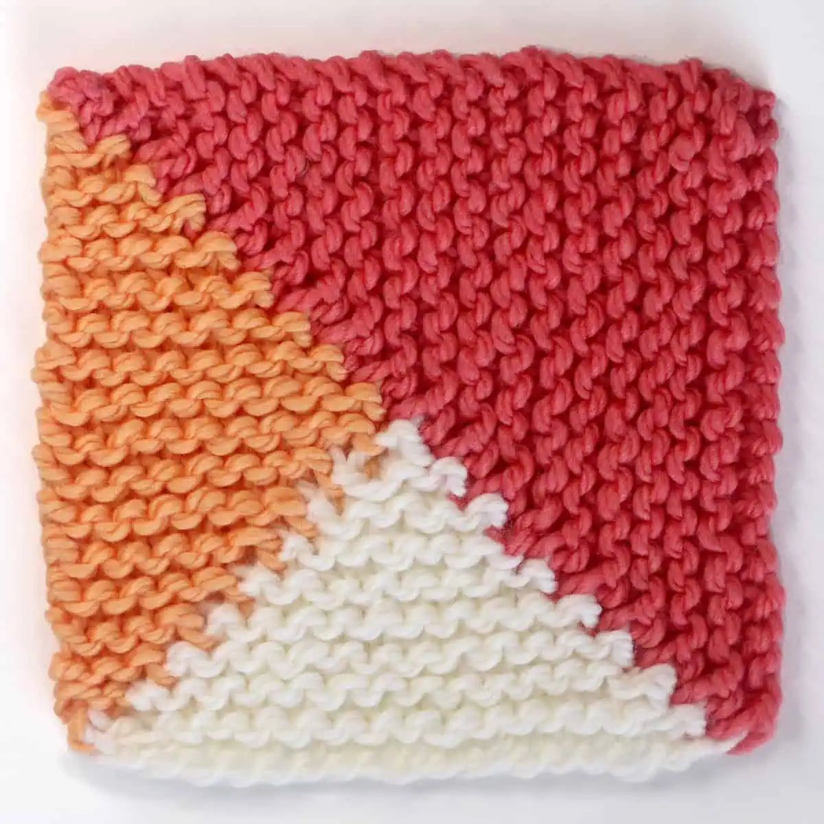 Knitted Split Quarter Square Triangle Knitting Pattern in white, pink, and orange yarn colors.