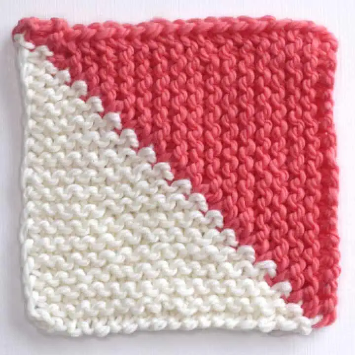 Mitered Half Square Triangle Knitted in white and dark orange yarn colors.