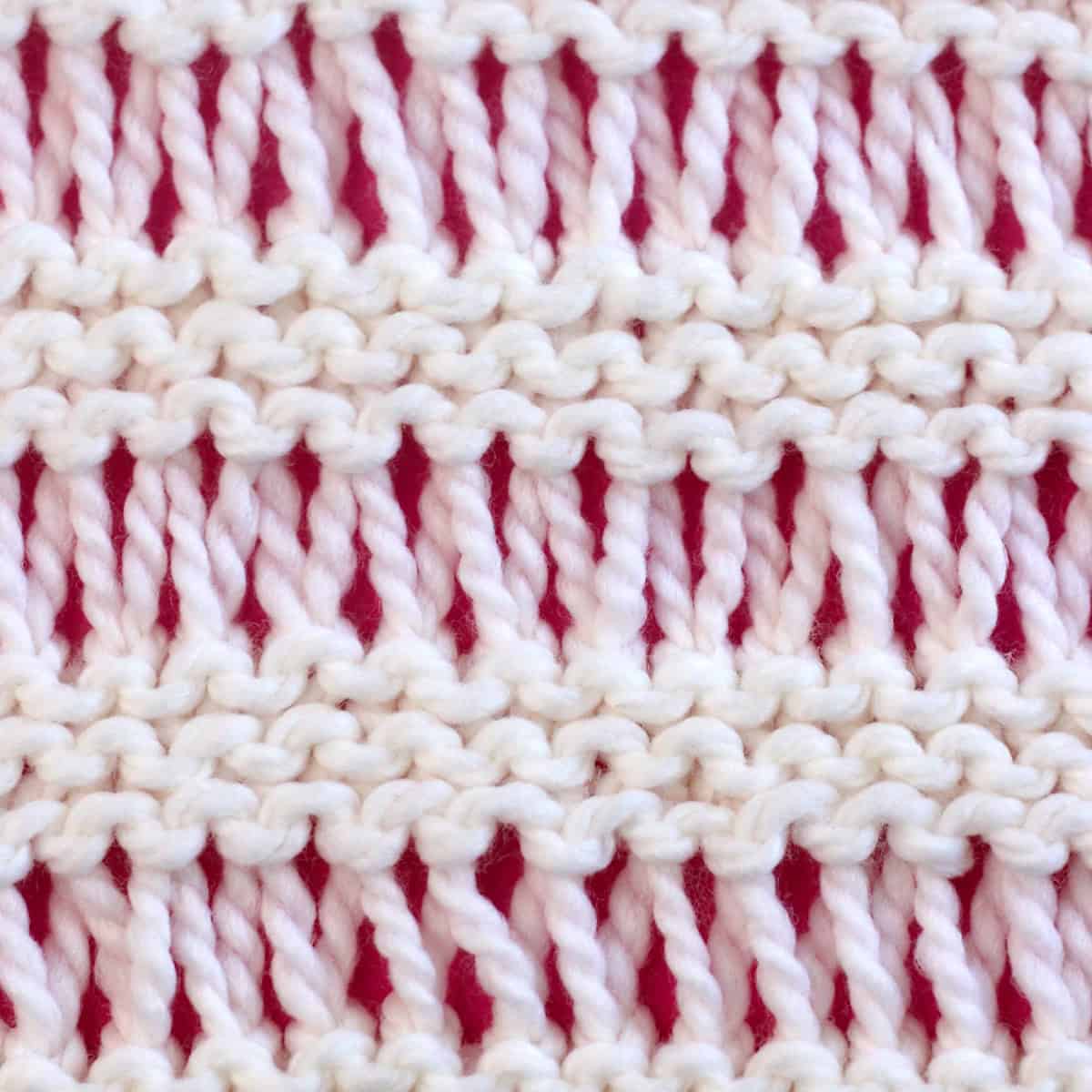 Drop stitch knitted with white yarn on a pink background.