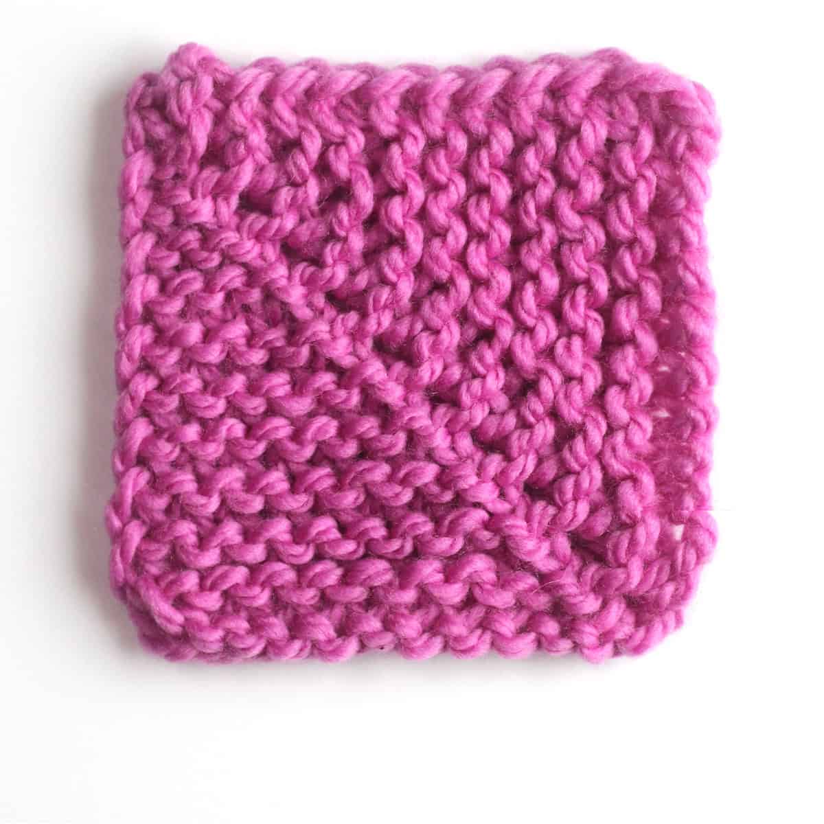 Mitered square knitted with center decreases in purple colored yarn.