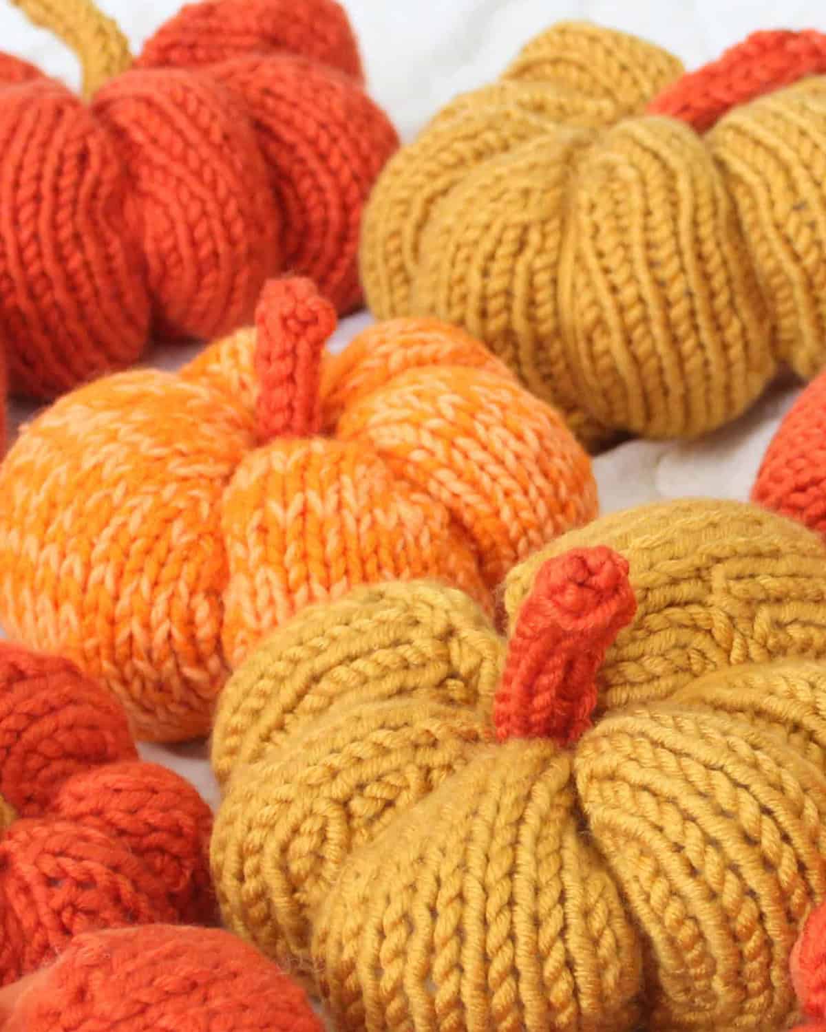 Knitted pumpkin softies in orange and yellow yarn colors.