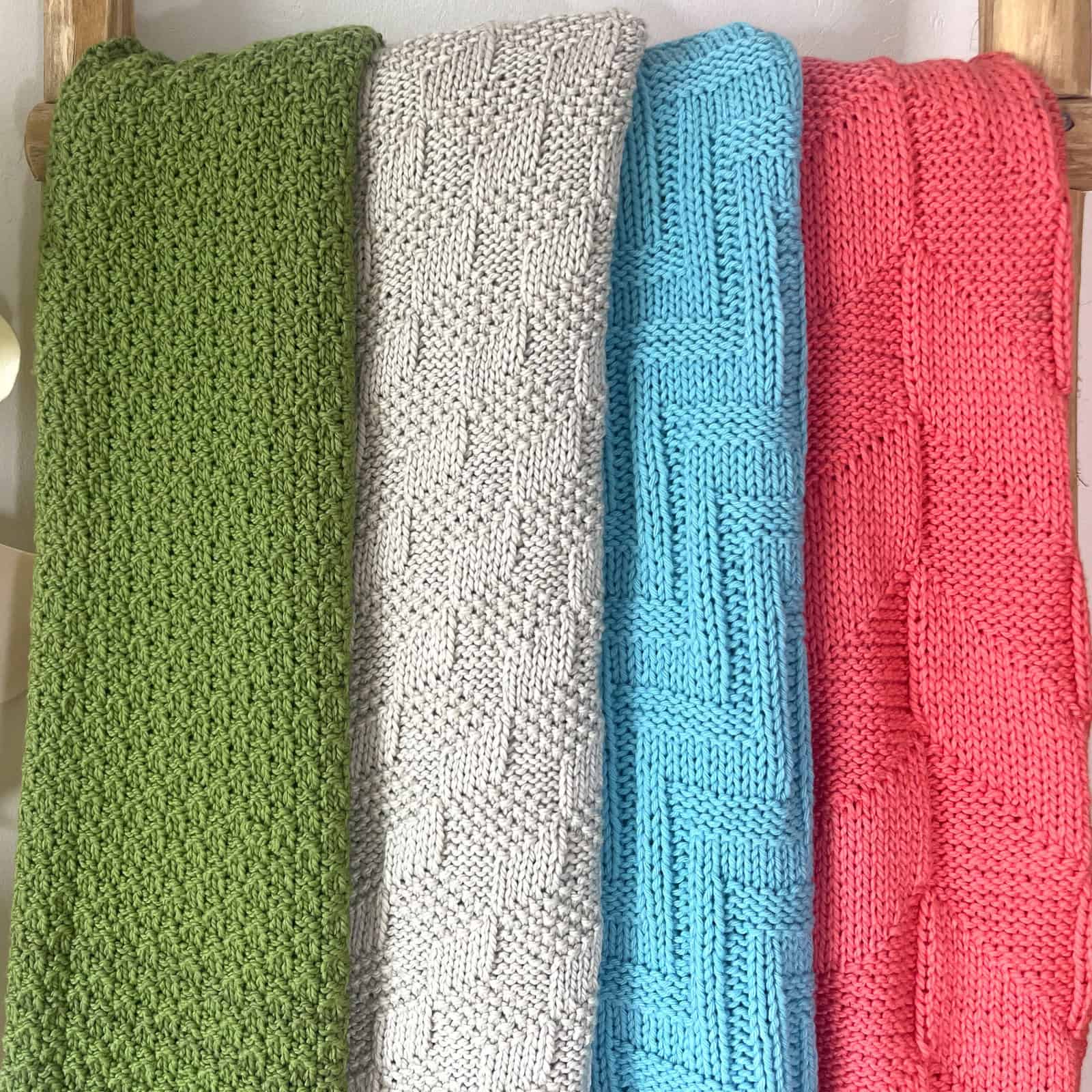 Four knitted blankets displayed on a wooden ladder.