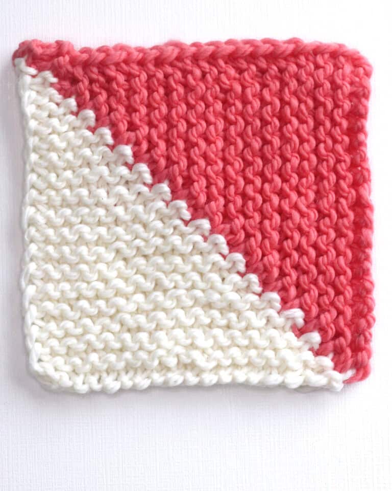 Mitered square half triangle knitted with white and orange colored yarn.