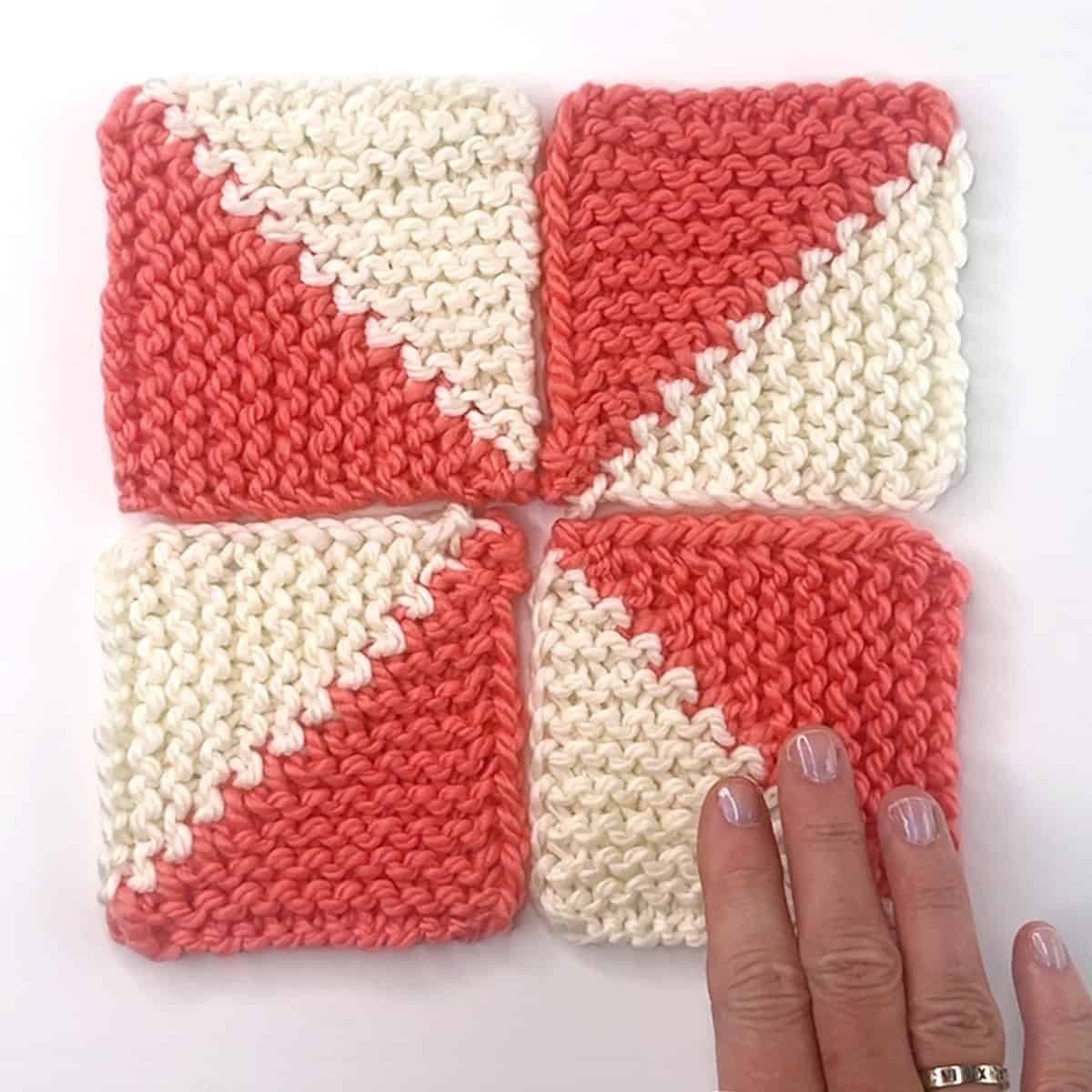 Four half-triangle knitted mitered squares arranged in a pinwheel design.