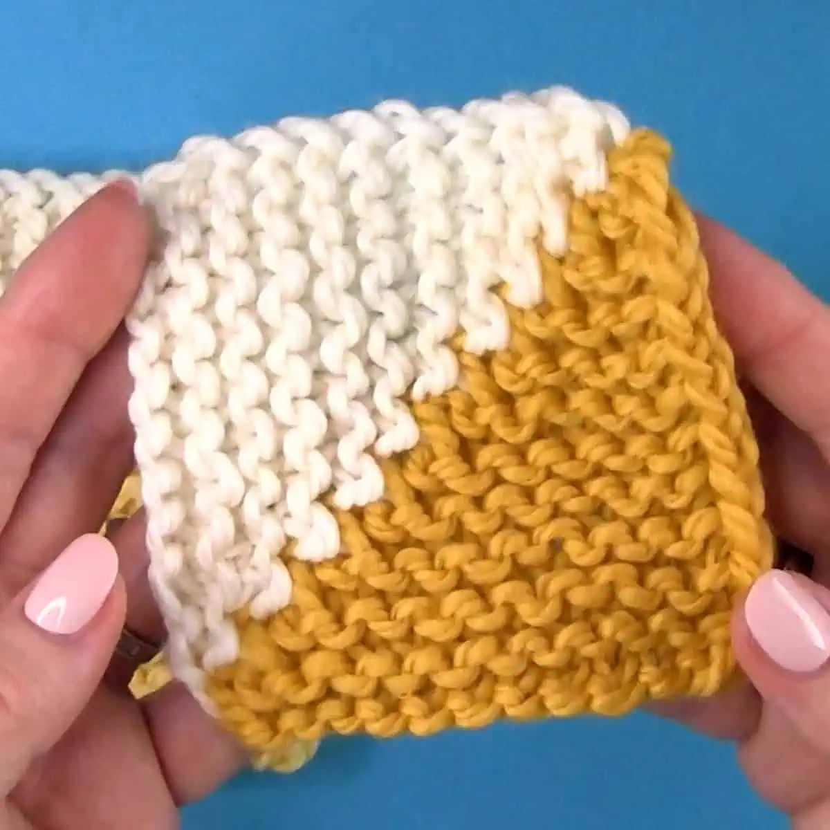 A half-triangle knitted mitered squares in white and yellow yarn colors.