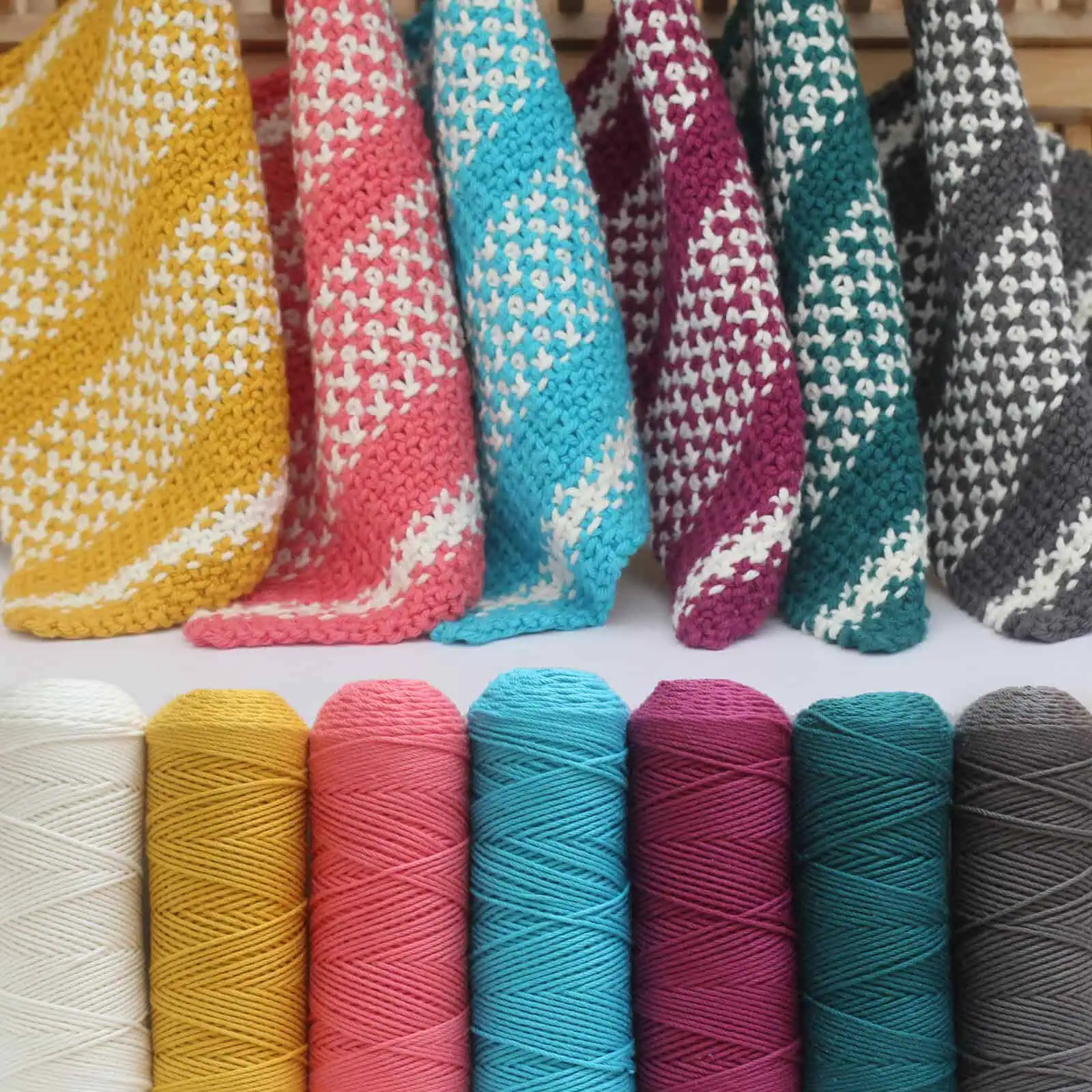 Six different knitted linen stitch dishcloths and yarn skeins.