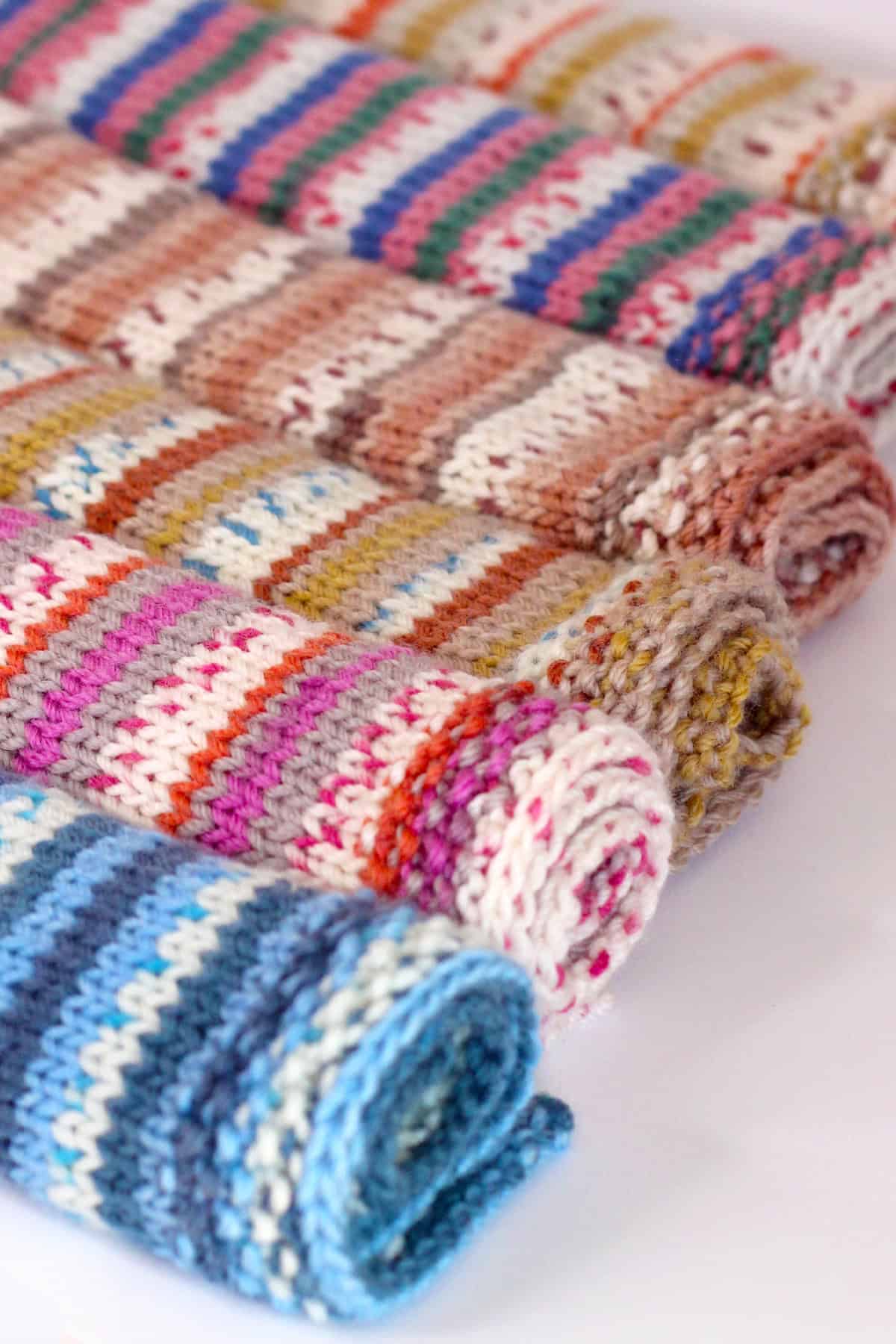 Fairyland Snuggles Baby Blankets in multiple yarn colors rolled up.